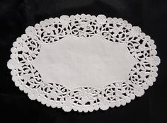 a white doily on a black background with an empty piece of paper in the middle