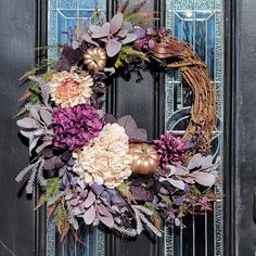 a wreath with flowers and leaves on the front door