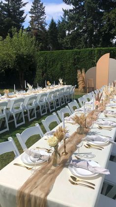 a long table set up with plates and place settings for an outdoor wedding reception in the garden