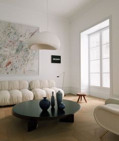 a living room filled with furniture and a large painting on the wall above it's coffee table