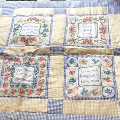 two quilted bedspreads with embroidered sayings on them, one is blue and the other has pink flowers