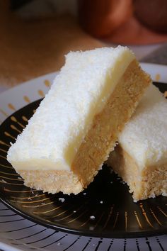 two pieces of white cake sitting on top of a black and white plate next to a fork