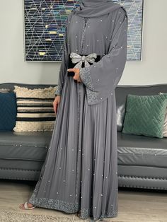 Elevate Your Elegance with Our Occasion Abaya Set Indulge in luxury with our Occasion Abaya Set, available in sophisticated Grey hues. This four-piece ensemble is a masterpiece of design, featuring convenient pop-up buttons for effortless wear. Exquisite Details, Unmatched Comfort Adorned with intricate gemstone embellishments, the outer jacket abaya is gracefully separated from the inner closed abaya. The inner layer is crafted from 100% Premium Nida fabric, ensuring lightweight and sumptuously