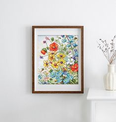 a white table with a vase and some flowers on it next to a framed painting