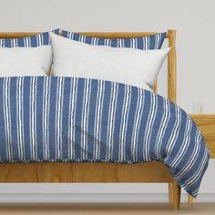 a bed with blue and white striped comforter on it's side, next to a wooden headboard