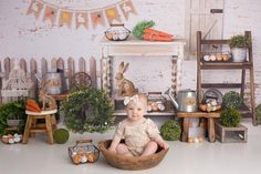 a baby sitting in a bowl surrounded by carrots and other vegetables on the floor