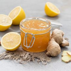 a glass jar filled with liquid next to sliced lemons and ginger on a table