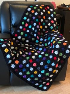 a black couch with a multicolored blanket on it