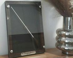 a silver vase sitting on top of a wooden table next to a metal framed object