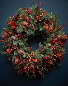 a christmas wreath with red berries and green leaves on a dark background, surrounded by greenery