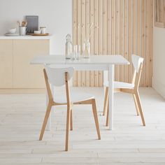 a white table and two chairs in a room with wood paneling on the walls