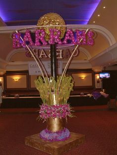 there is a sign that says mardi gras on top of a pole with flowers in it