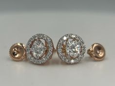 three diamond stud earrings on a white surface with the top one being surrounded by smaller round diamonds