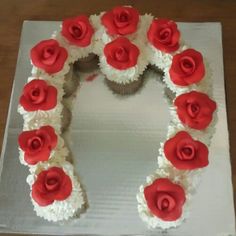 a cake with white frosting and red roses on it is shaped like the letter o