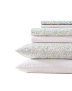 four pillows stacked on top of each other with pink and blue floral print sheets in front of them