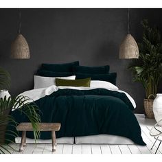 a bed with red and white comforters in a room next to potted plants