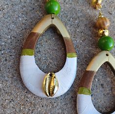 two pairs of earrings with green beads on the bottom and one has a shell in it