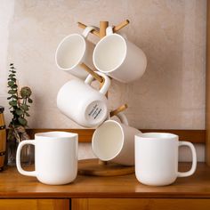 white coffee cups are stacked on top of each other in front of a wooden shelf