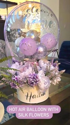 a vase filled with lots of purple and white flowers on top of a glass table