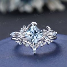 a ring with an aqua blue topazte surrounded by white diamonds on a blue cloth