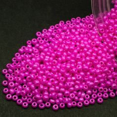 pink beads are being poured into a container