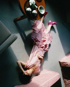 a woman in a pink dress laying on the floor