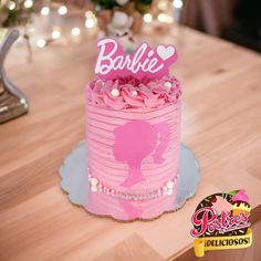 a pink cake sitting on top of a wooden table next to a sign that says barbie