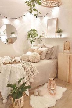 a white bedroom with lots of pillows and blankets on the bed, potted plants