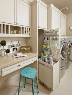 a kitchen with white cabinets and a blue stool in front of the dishwasher