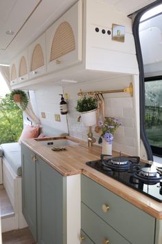 the interior of a camper with wood counter tops and green cabinets, along with an oven