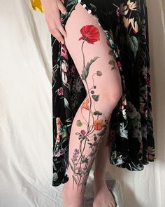 a woman's legs with tattoos on them and flowers all over the leg area