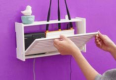 a person is holding up a shelf with wires attached to it