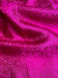 a close up view of a pink and black fabric with intricate designs on the side