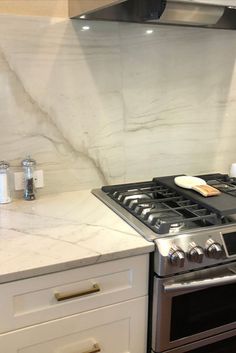 a stove top oven sitting inside of a kitchen next to a counter and drawers with utensils on it