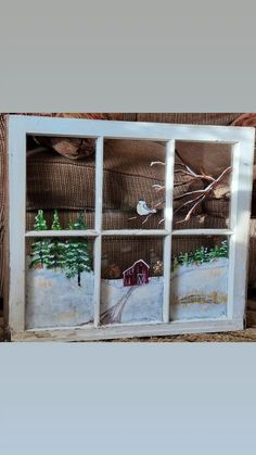 an old window is painted with winter scenes and trees in the windowsill, as well as a red barn