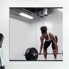 a woman lifting a barbell in front of a mirror