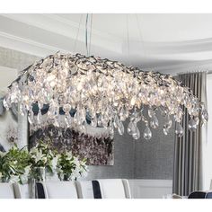 a chandelier hanging from the ceiling in a dining room with white chairs and table