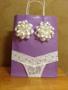 a purple paper bag with white lace and two large bows on the front, sitting on a wooden table