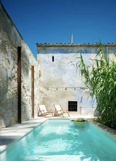 an outdoor swimming pool with lounge chairs next to it