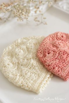 two crocheted hats sitting on top of a white plate next to each other