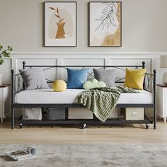 a daybed with pillows and blankets on it in a room next to two pictures