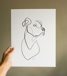 a hand holding up a drawing of a dog