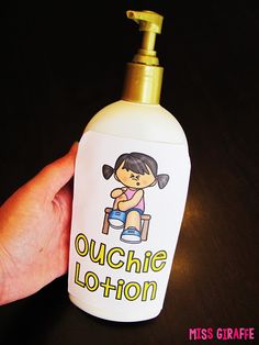 a hand is holding a bottle with a cartoon girl on it that says ouchie lotion