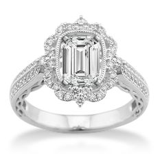 an emerald and diamond engagement ring on a white background with the center stone surrounded by diamonds