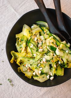 a black bowl filled with cucumber and feta cheese on top of a table