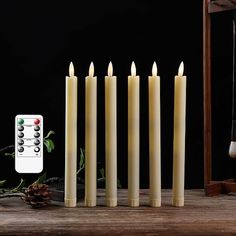 a group of candles sitting on top of a wooden table next to a remote control