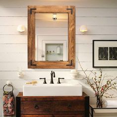 a bathroom with a sink, mirror and pictures on the wall above it's counter