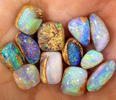 a person's hand holding several different colored opalite stones in their palm