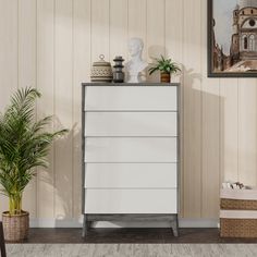 a white chest of drawers sitting next to a potted plant in a living room