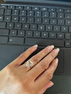 a woman's hand with a ring on her finger next to a computer keyboard